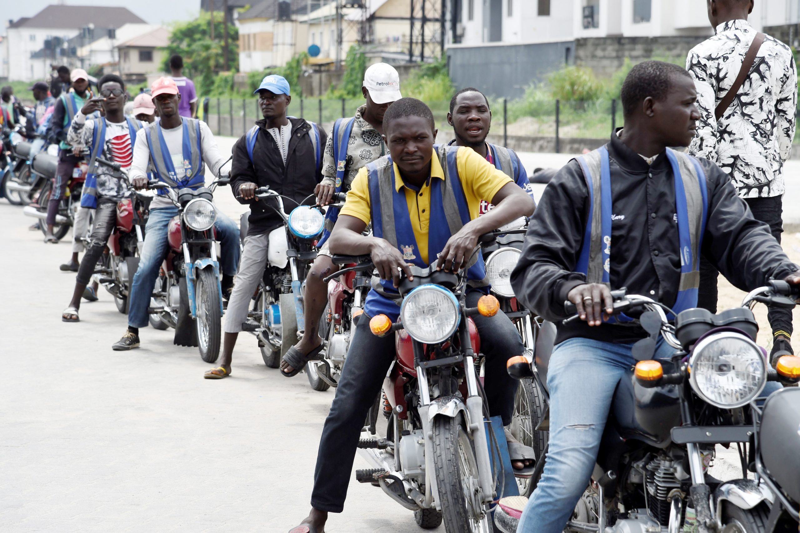 Regular motorcycle taxis queue for passengers without helmet or kits for safety unlike Uber-style branded motorbike taxis in Lagos, on September 4, 2019. - A growing number of ride hailing services have stepped into the chaos -- bringing order to the "okada" motorbike taxis that have long whizzed perilously around Lagos. Before the systems launched, Lagosians in a hurry had to put their faith in the army of unregulated "okada" riders weaving hazardously through the traffic. But with the emergence of the Uber-style motorbike taxis, motorists often dump their cars for one of a raft of new motorbike ride hailing apps that developers hope can speed up journeys and to beat gridlock on Lagos roads for the roughly 20 millions residents of the economic capital. (Photo by PIUS UTOMI EKPEI / AFP)        (Photo credit should read PIUS UTOMI EKPEI/AFP via Getty Images)